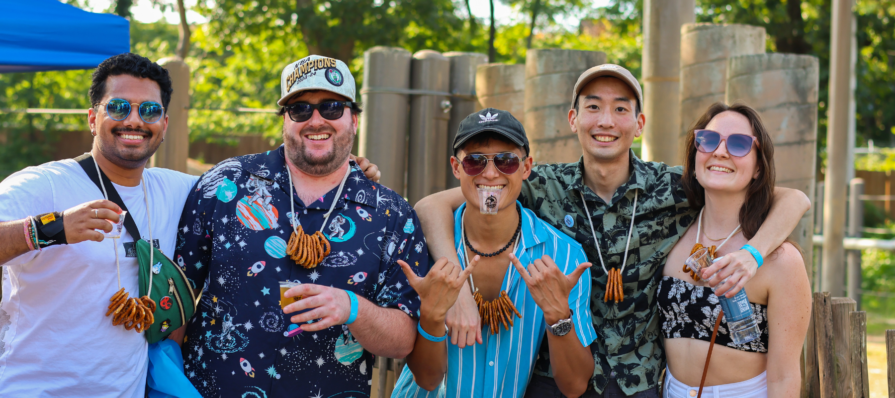 Brew at the Zoo attendees smiling and posing while wearing pretzel necklaces and holding drink tasting cups.